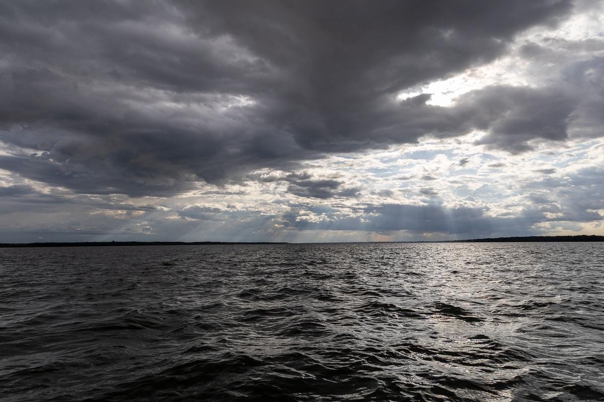 Cielo cargado de nubes sobre el río, con los rayos de sol abriéndose paso en plena temporada de lluvias